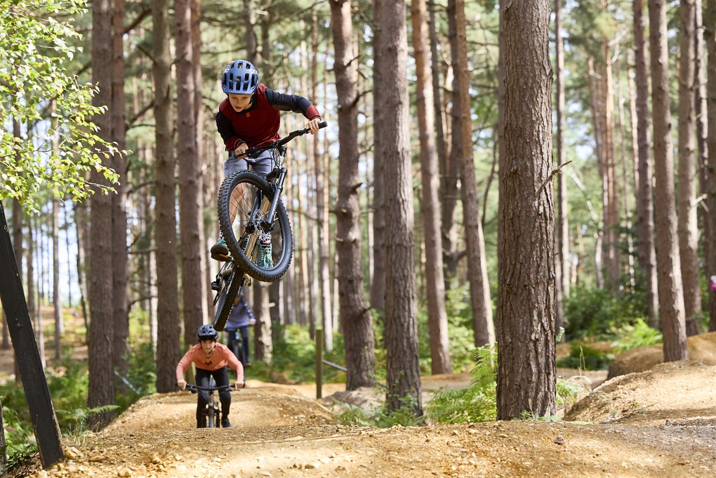 A child jumping a Frog mountain bike on a woodland trail